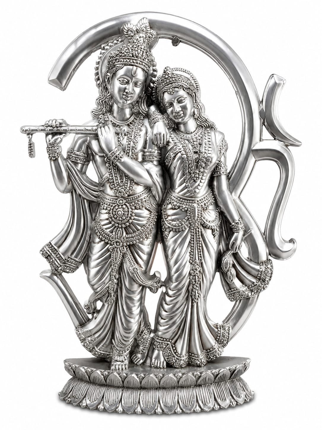Radha and Krishna: Krishna stands on the left, cross-legged in his classic posture, holding a decorative flute (bansuri) to his lips. Radha leans gently against his shoulder on the right, looking toward him. Both figures are adorned with intricate jewelry, including elaborate crowns (mukuts), multiple layered necklaces, armlets, bracelets, and detailed traditional garments with deeply carved folds. Radha Krishna